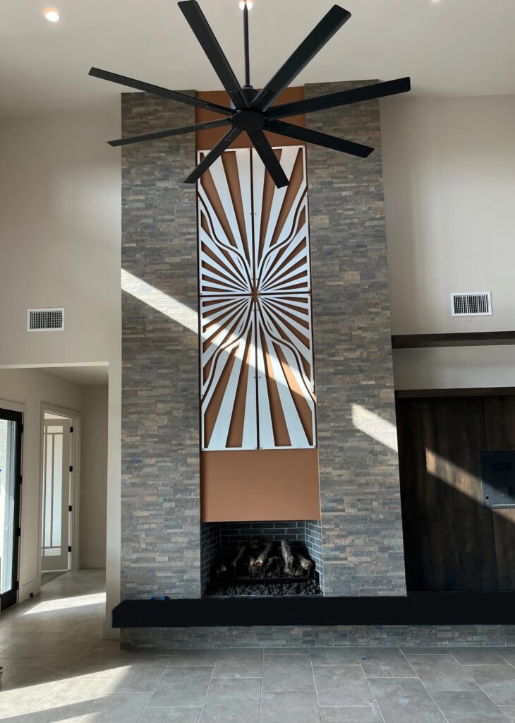 A modern living room features a large stone fireplace, decorative wall art, and a ceiling fan.